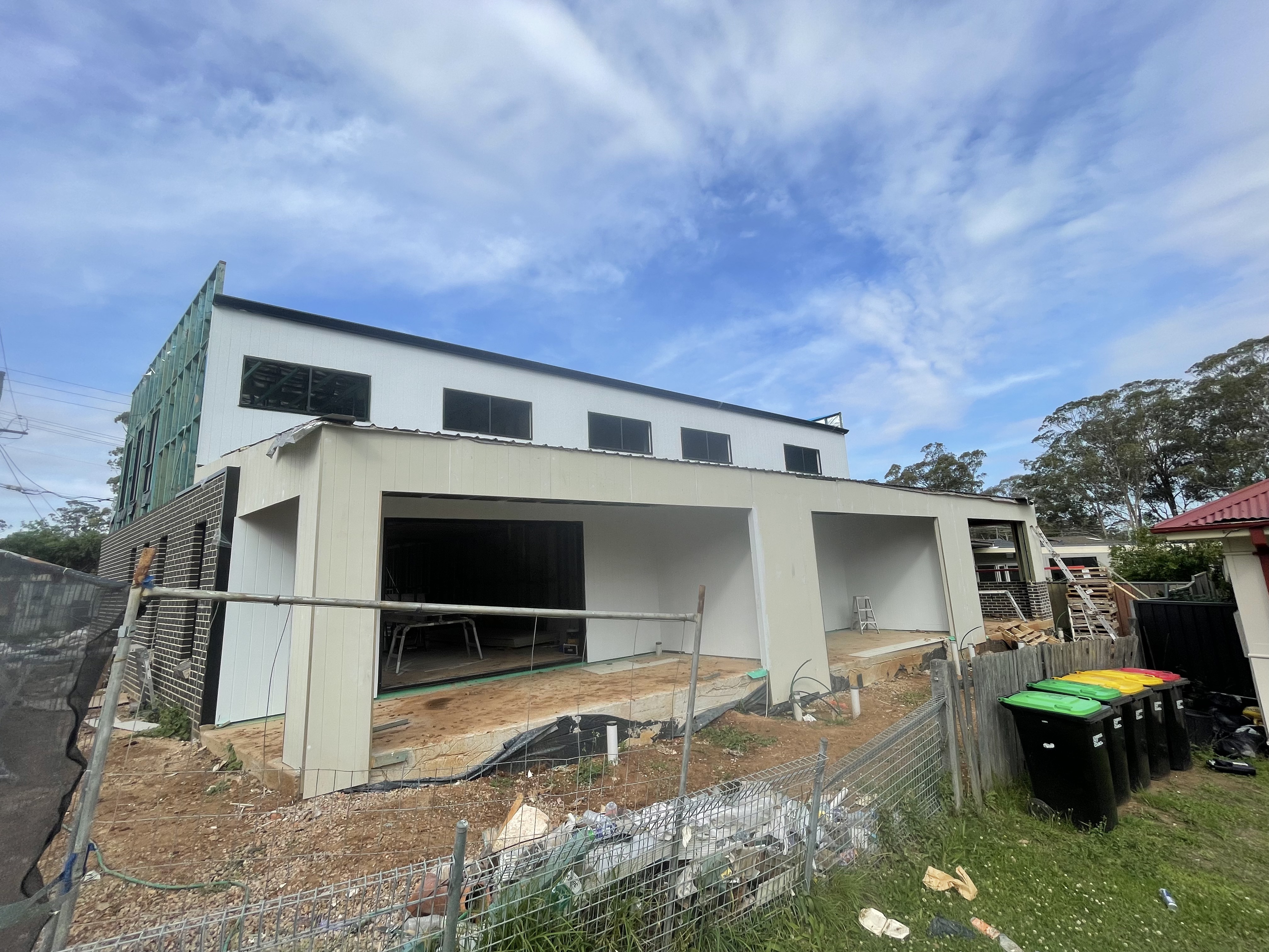 Residential extension under construction with cladding and brick base